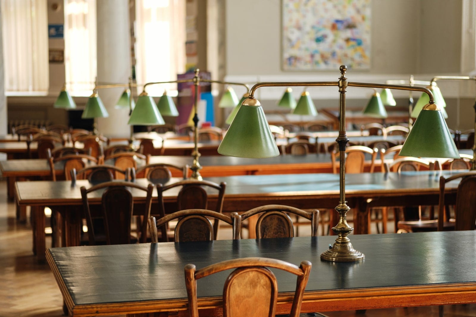 Empty reading room desks under shaded library lamps