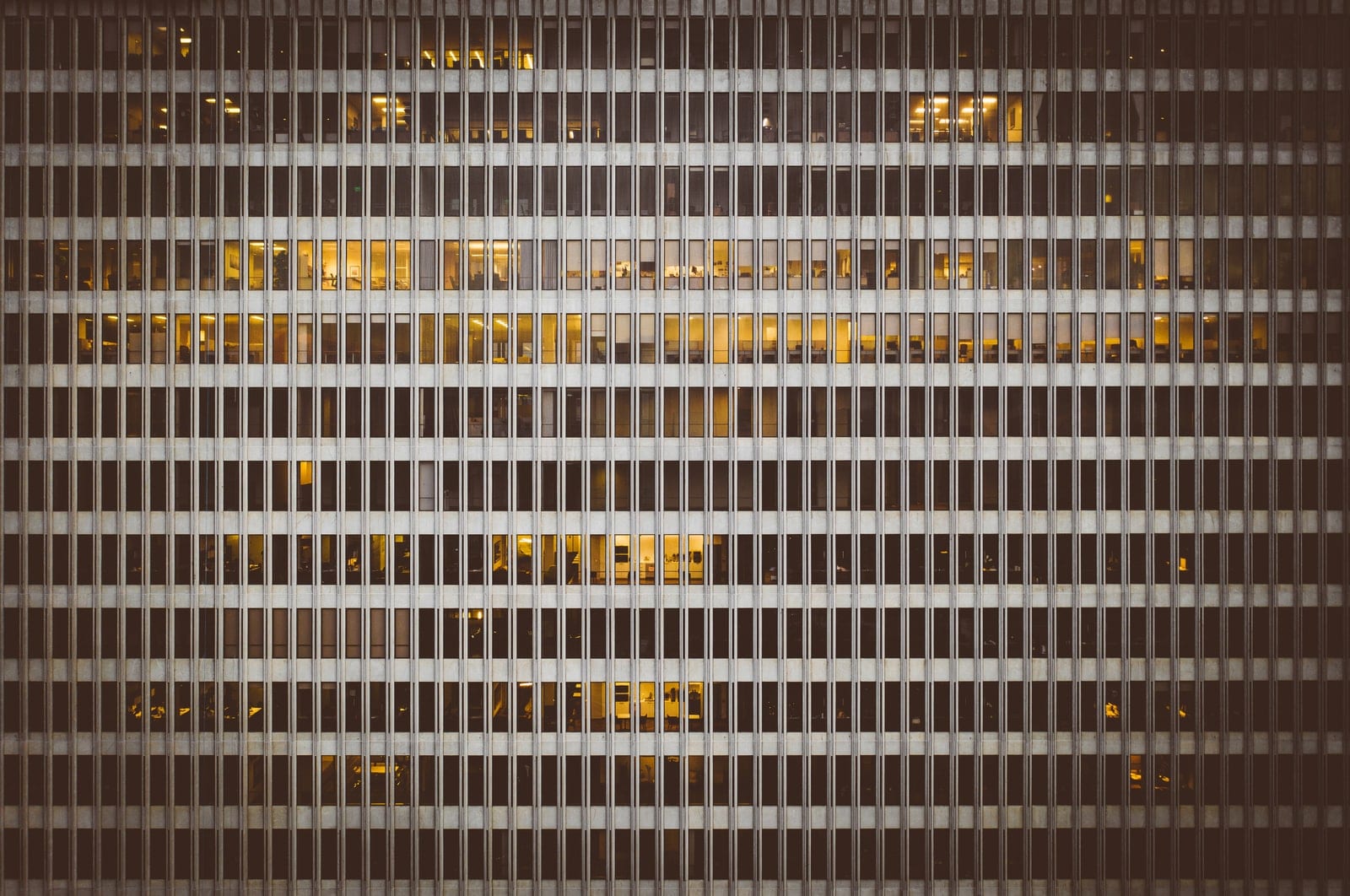 Lit windows in the grid of an office tower facade at night